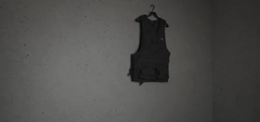 Black tactical weighted vest lying on a concrete gym floor next to a barbell plate, dramatic overhead lighting, dark moody atmosphere, industrial setting, masterpiece, best quality, highly detailed, sharp focus, professional photography