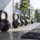 ** Verschiedene Kettlebells in mehreren Gewichten nebeneinander auf dem Boden eines hellen Home-Gyms