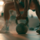 ** Athlet trainiert zuhause mit einer Kettlebell im Ganzkörper-Workout, Swing-Bewegung