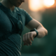 ** Läufer mit Brustgurt und Sportuhr am Handgelenk kontrolliert seine Herzfrequenz beim Training