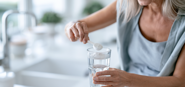 Frau um die 50 rührt Kreatinpulver in ein Glas Wasser