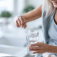 Frau um die 50 rührt Kreatinpulver in ein Glas Wasser