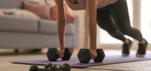 Frau trainiert mit Kurzhanteln auf der Matte im Wohnzimmer