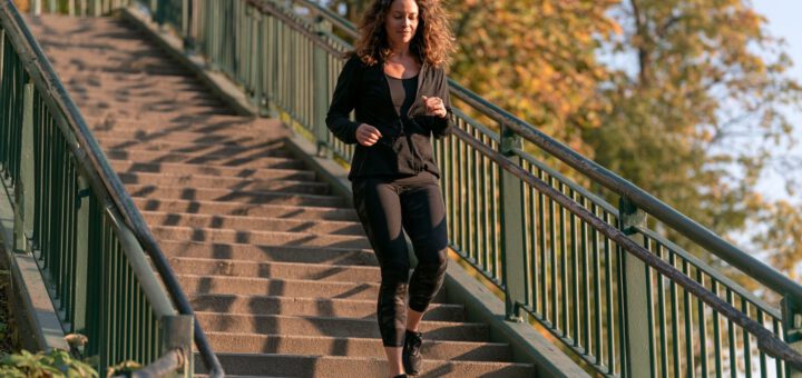 Frau kommt bei Morgenlicht eine lange Außentreppe im Park herunter