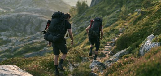 Zwei Wanderer mit Rucksäcken steigen einen felsigen Bergpfad ab