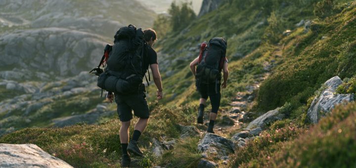 Zwei Wanderer mit Rucksäcken steigen einen felsigen Bergpfad ab