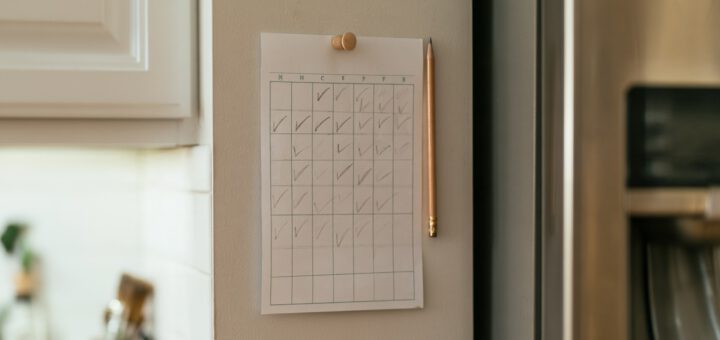 Selbstgezeichneter Gewohnheitskalender mit Häkchen und einzelnen leeren Tagen an der Küchenwand