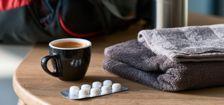 Espresso und Koffeinkapseln neben einer Sporttasche vor dem Training