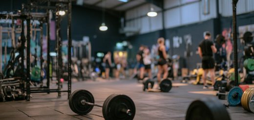 Blick über eine belegte Trainingsfläche mit Langhanteln im Vordergrund und Racks im Hintergrund