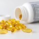 Goldgelbe Omega-3-Fischölkapseln vor einer umgekippten Dose mit Nährwerttabelle auf dem Etikett