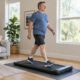 Mann um die 50 geht zu Hause zügig auf einem Walking Pad, Wohnzimmer bei Tageslicht